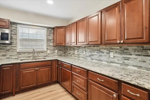 a kitchen with stainless steel appliances granite countertop wooden cabinets a sink and dishwasher with wooden floor