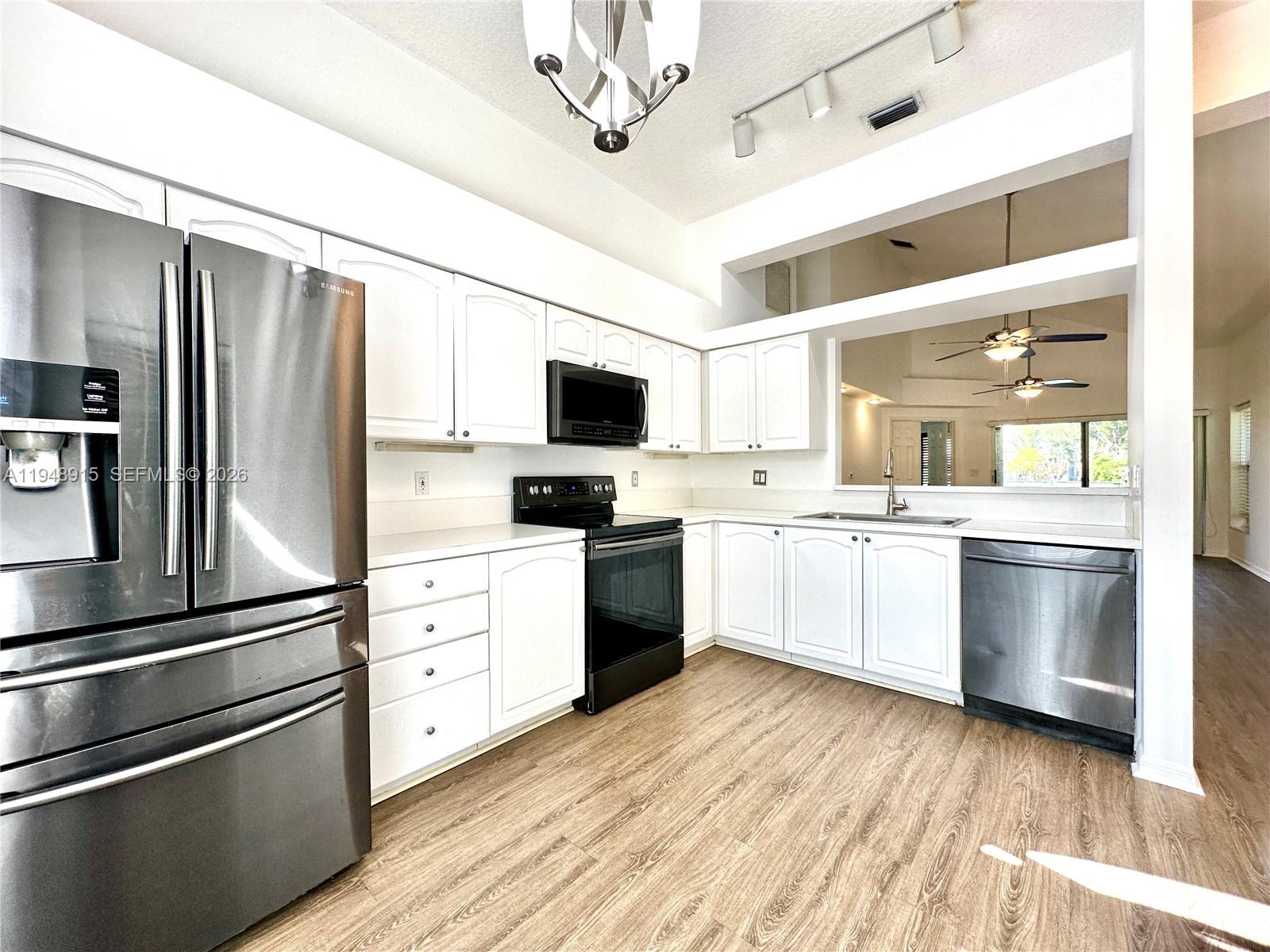 1013 Via Jardin Riviera Beach, FL 33418 - Photo 7 of 18 a kitchen with a refrigerator and white cabinets