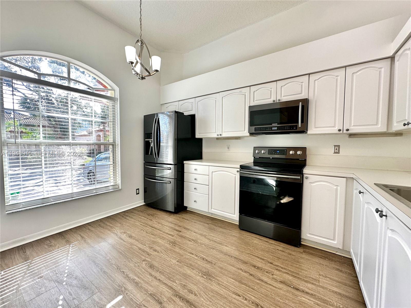 1013 Via Jardin Riviera Beach, FL 33418 - Photo 8 of 18 a kitchen with stainless steel appliances granite countertop a refrigerator a stove a sink dishwasher a microwave oven with cabinets and wooden floor