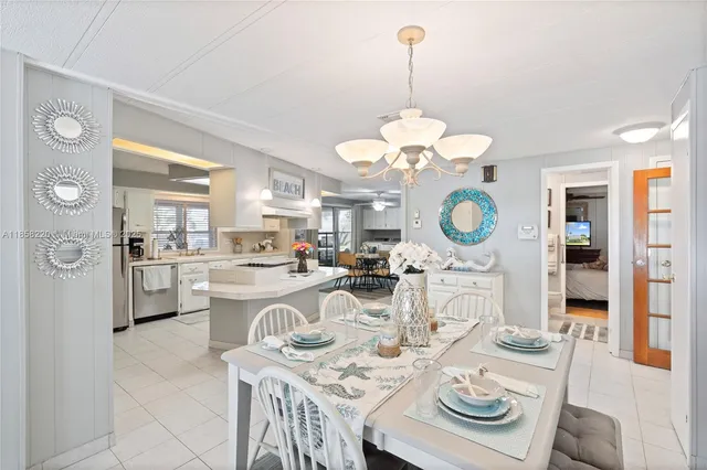 a kitchen with stainless steel appliances kitchen island granite countertop a table chairs and a refrigerator