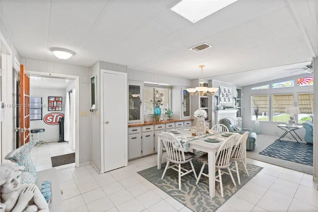a view of a dining room with furniture a chandelier and kitchen view