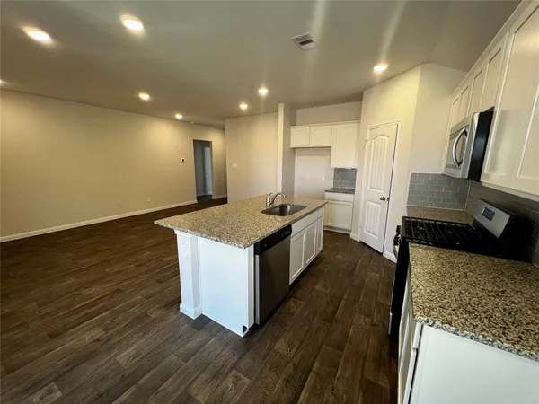 a kitchen with stainless steel appliances granite countertop a sink a stove top oven a counter space and cabinets