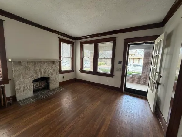 wooden floor fireplace and windows in an empty room