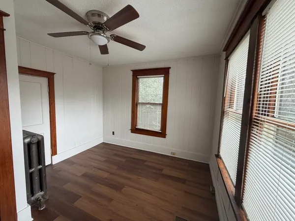 a view of empty room with wooden floor and fan