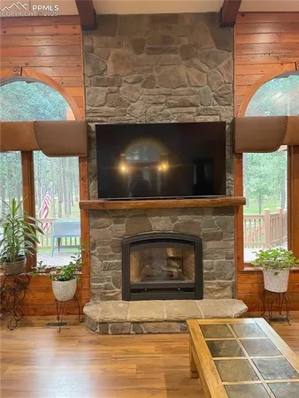 a living room with a fireplace a flat screen tv and a floor to ceiling window