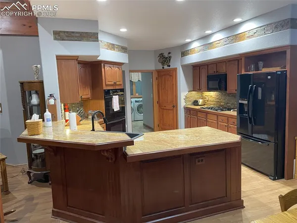 a kitchen with stainless steel appliances kitchen island granite countertop a sink refrigerator and cabinets