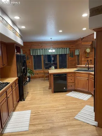 a large kitchen with stainless steel appliances a sink counter space and wooden floor