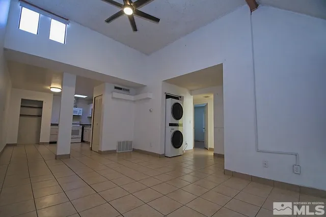 a view of an empty room with window and chandelier fan
