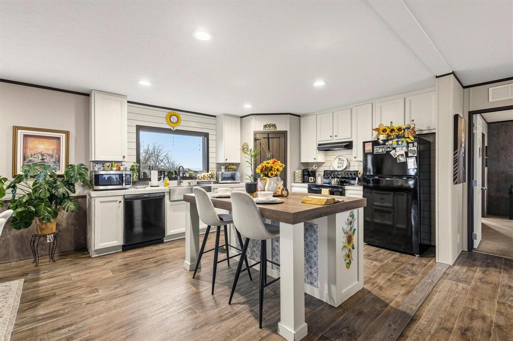 1517 Bennett Road Howe, TX 75459 - Photo 37 of 40 Kitchen with black appliances, dark wood-style floors, a kitchen breakfast bar, white cabinetry, and recessed lighting