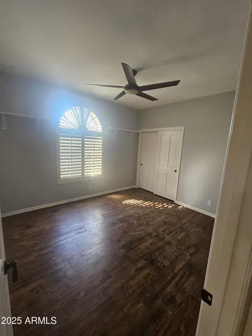 an empty room with wooden floor fan and windows