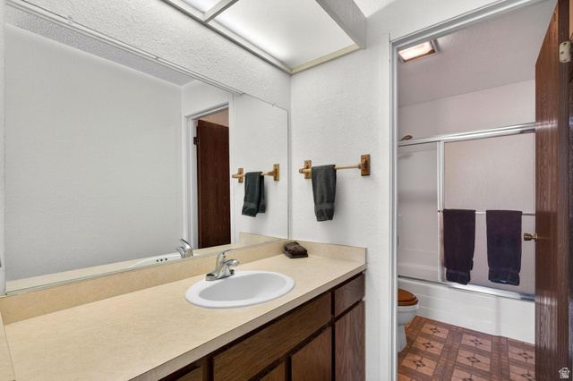 407 South Vasels Road, Unit 24 Brian Head, UT 84719 - Photo 20 of 63 Full bathroom featuring bath / shower combo with glass door, vanity, dark floors, and a textured wall