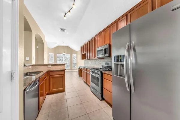 a large kitchen with stainless steel appliances granite countertop a stove and a refrigerator