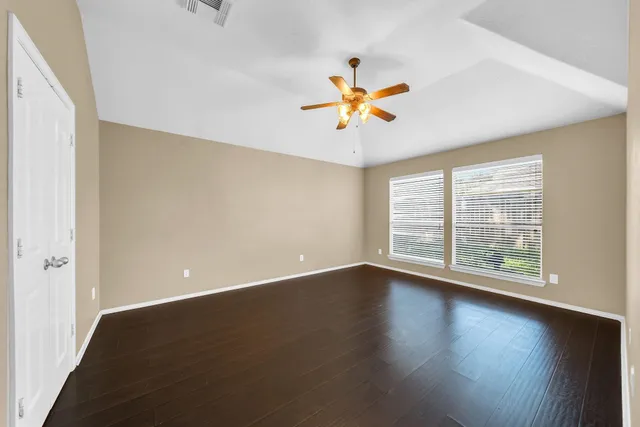 an empty room with a window and a ceiling fan