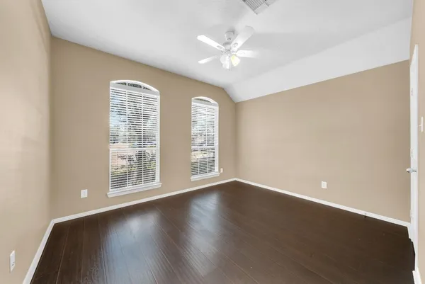 an empty room with wooden floor chandelier fan and windows