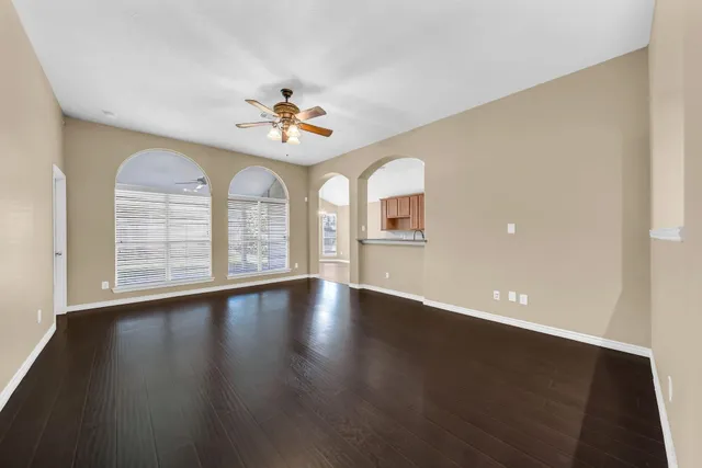 a view of an empty room with a window and wooden floor