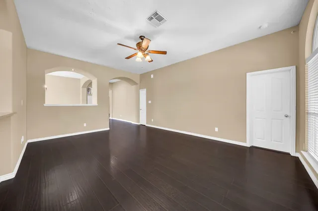 a view of an empty room with wooden floor and a window