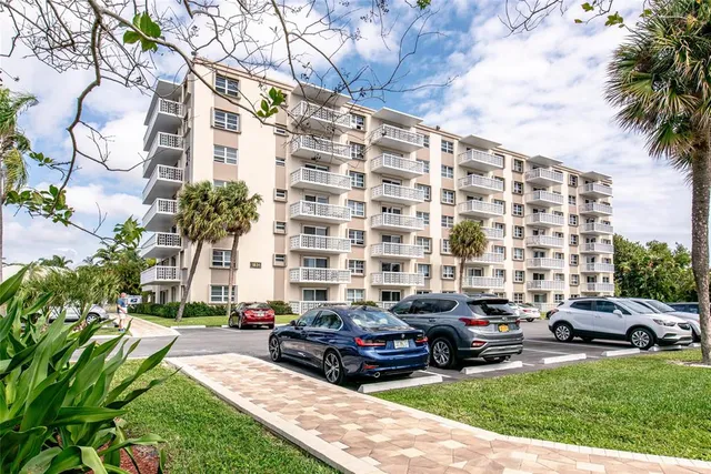 a car parked in front of a brick house with a large tree