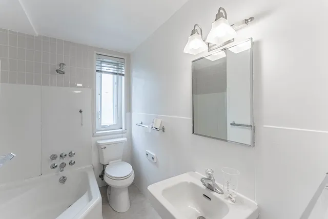 a bathroom with a toilet a sink a mirror and a tub