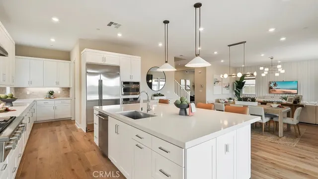 a kitchen with stainless steel appliances kitchen island granite countertop a sink a stove and a wooden floors