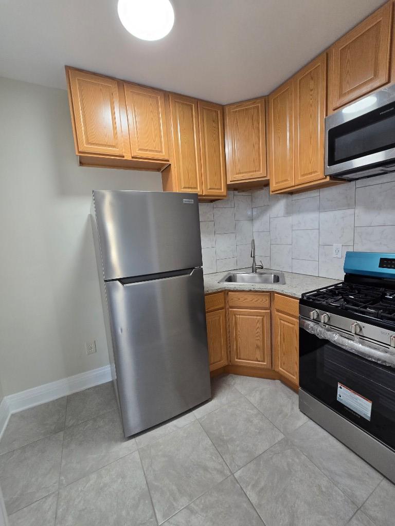 754 Park Place, Unit 9 Brooklyn, NY 11216 - Photo 4 of 6 a kitchen with a refrigerator sink and cabinets