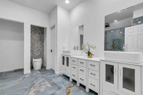 a spacious bathroom with double sink a toilet a shower and a window