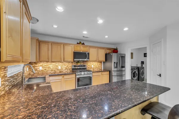 a kitchen with stainless steel appliances granite countertop a sink refrigerator and cabinets