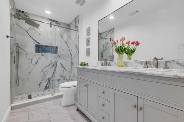 a bathroom with a granite countertop sink a toilet and a shower