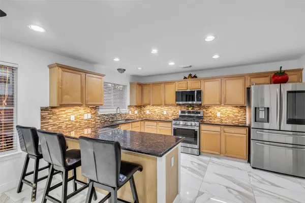 a kitchen with granite countertop stainless steel appliances a sink counter space and a window