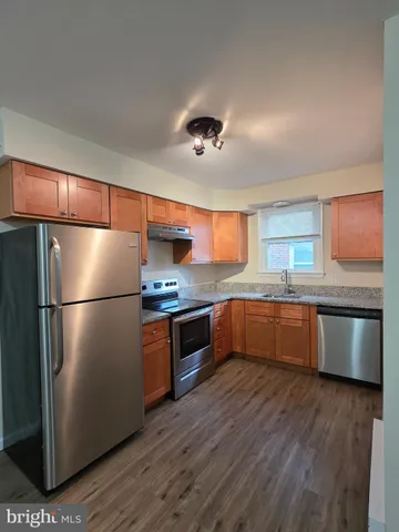 a kitchen with stainless steel appliances granite countertop a refrigerator a sink dishwasher a stove with wooden floors and cabinets