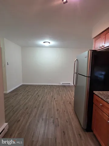 a view of a refrigerator in kitchen and an empty room