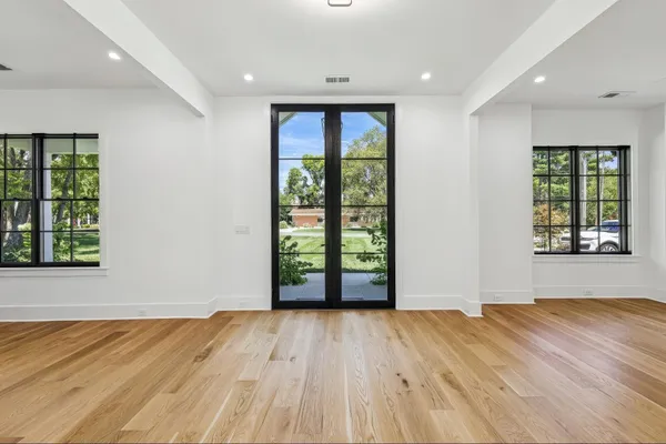 a view of an empty room with wooden floor and a window