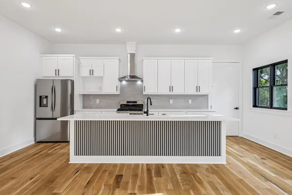 a front view of a house with a garden and trees