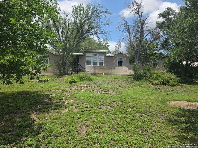 a view of a house with yard and trees in the background