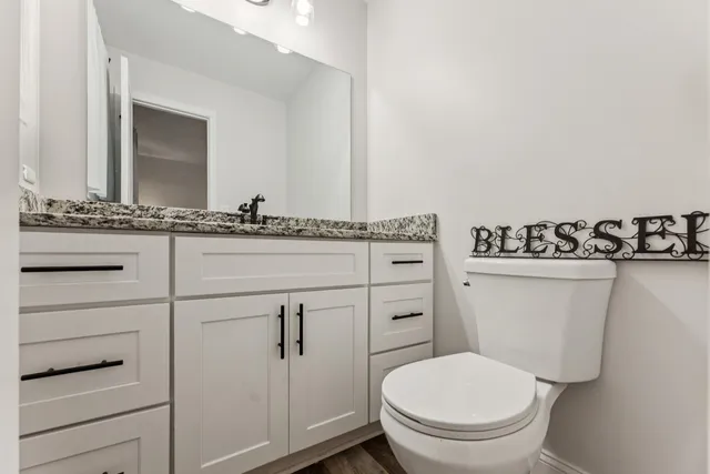 a bathroom with a granite countertop toilet sink and mirror