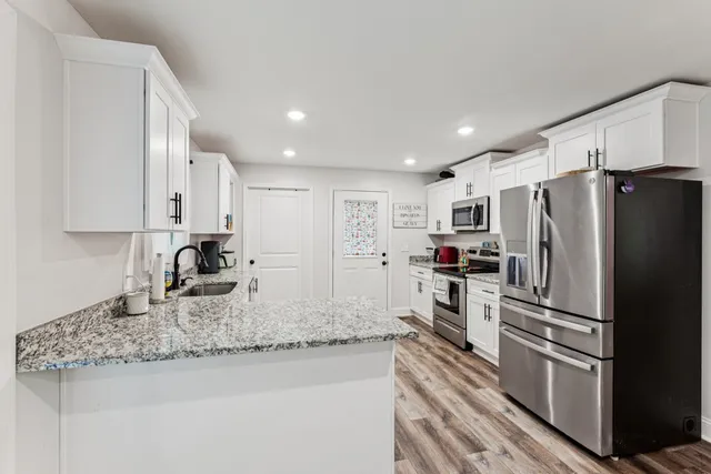 a kitchen with granite countertop kitchen island stainless steel appliances a refrigerator and a sink