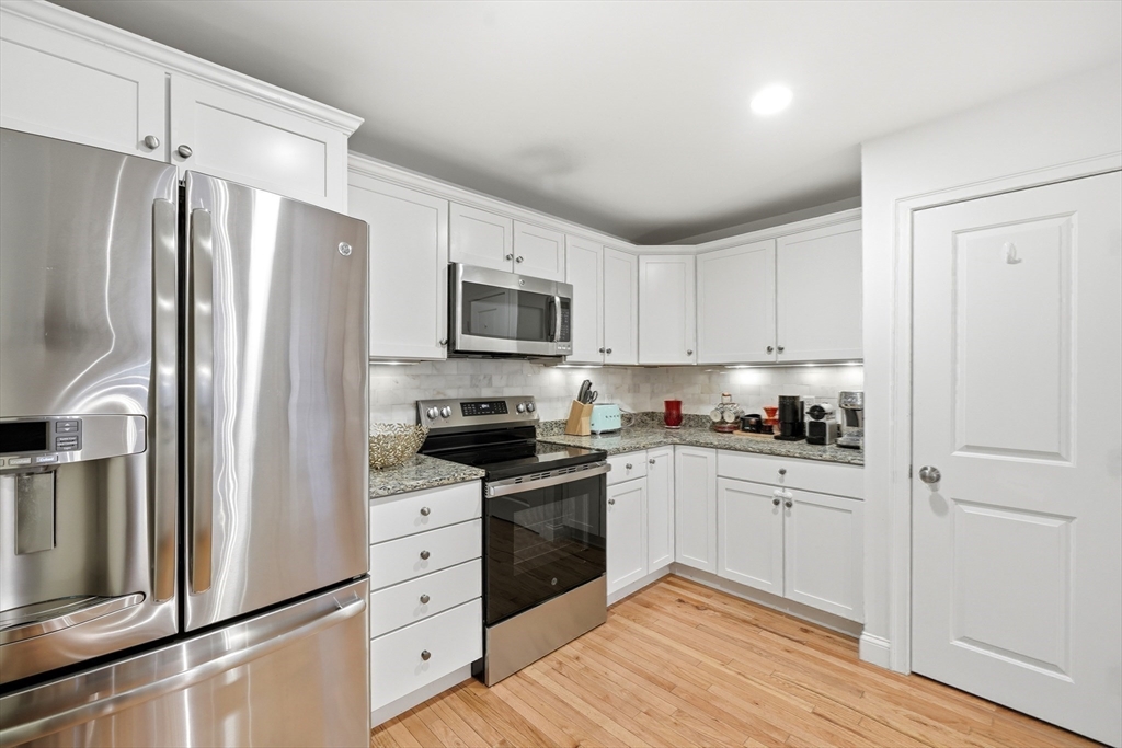 30 Webster Street, Unit 3 Needham, MA 02494 - Photo 21 of 38 a kitchen with white cabinets stainless steel appliances and wooden floor