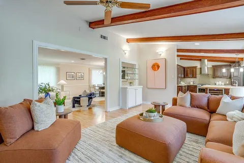 a living room with furniture kitchen view and a large window