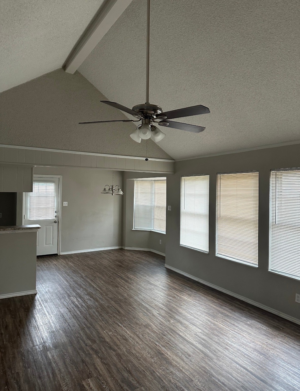 2106 Woodway Drive Woodbranch, TX 77357 - Photo 5 of 17 an empty room with wooden floor chandelier fan and windows
