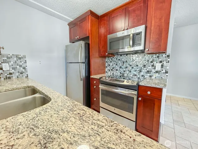 a kitchen with stainless steel appliances kitchen island granite countertop a refrigerator and a stove top oven