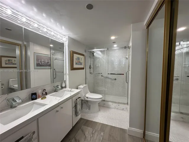 a bathroom with a double vanity sink toilet mirror and shower