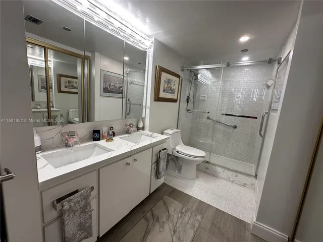 a bathroom with a double vanity sink toilet mirror and shower