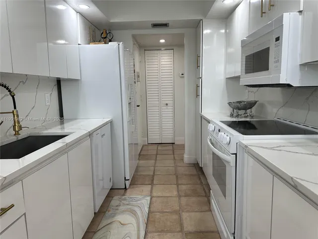 a kitchen with a sink dishwasher stove and white cabinets