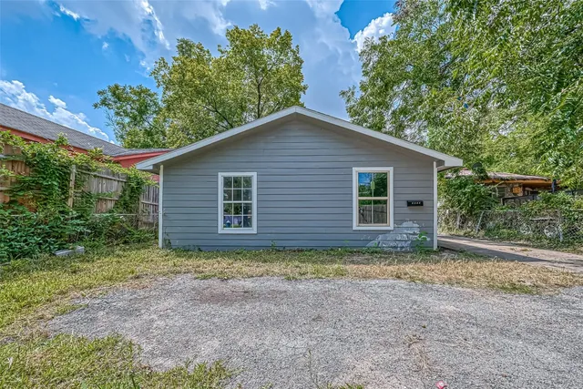 a view of a house with a small yard and large tree