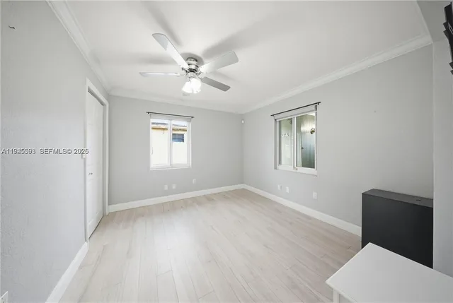 a view of empty room with wooden floor and fan
