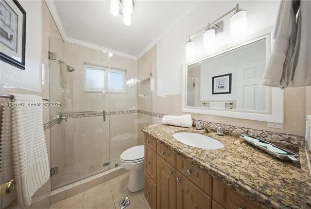 a bathroom with a granite countertop sink a mirror a toilet and a shower