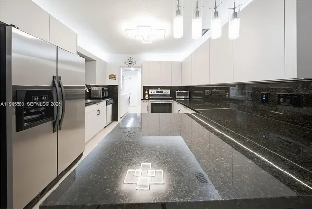 a large kitchen with stainless steel appliances a large counter top