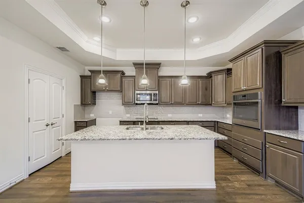 a large kitchen with stainless steel appliances kitchen island granite countertop a stove a refrigerator a oven and a sink with wooden floor