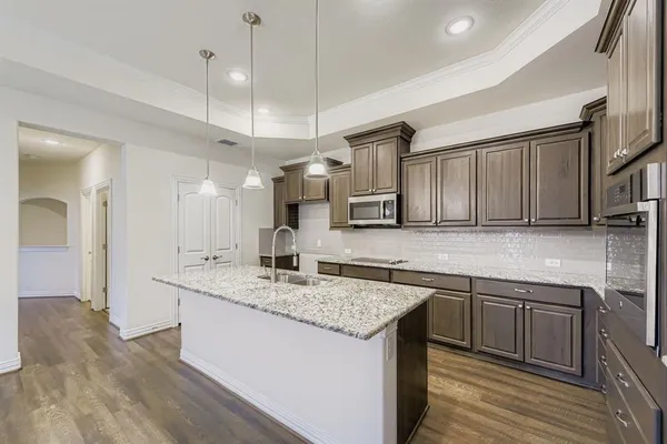 a kitchen with stainless steel appliances granite countertop a sink a stove and a wooden floors