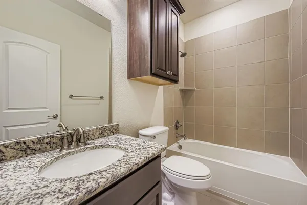 a bathroom with a granite countertop toilet a sink and a mirror