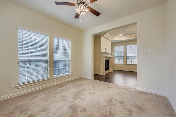 a view of an empty room with a window and kitchen view
